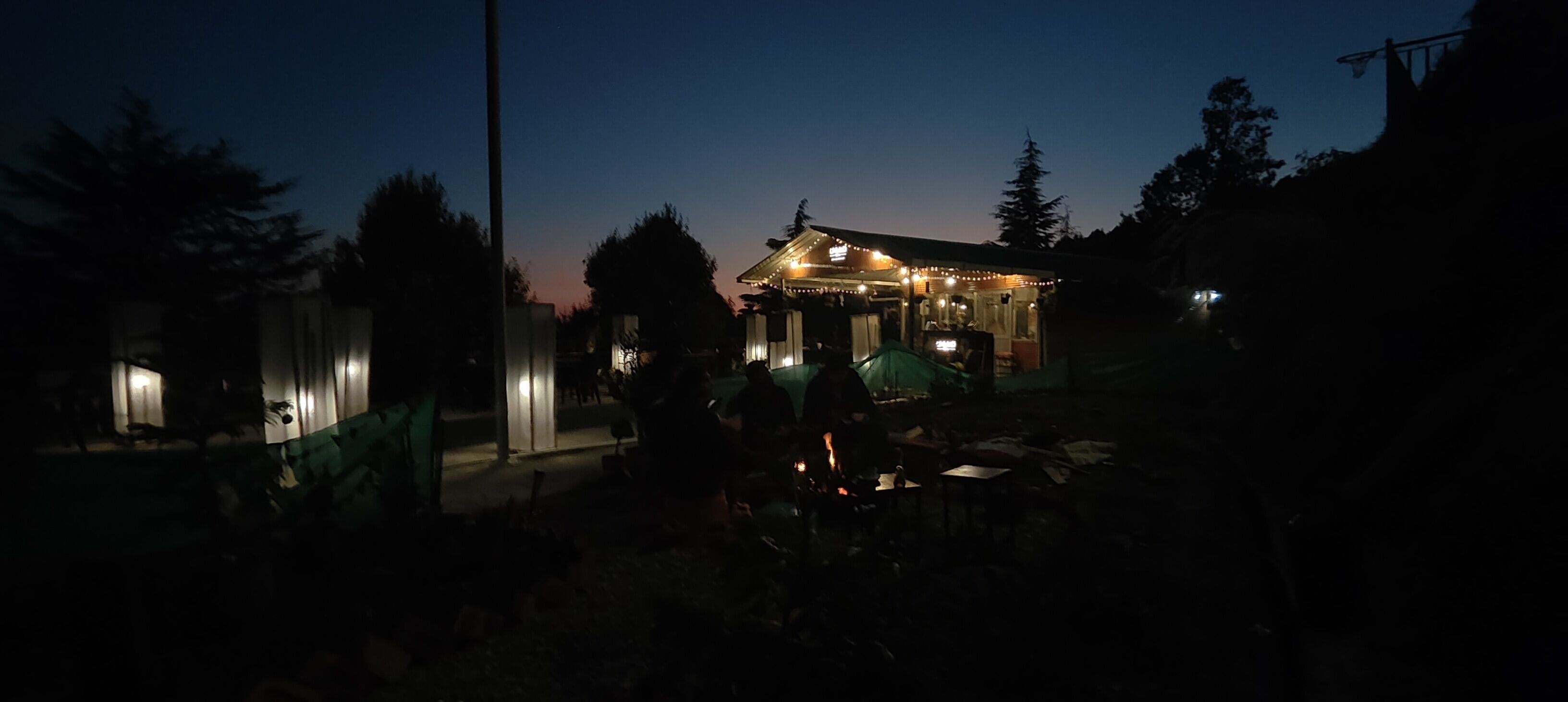 Un piccolo edificio illuminato con un portico, circondato da alberi.