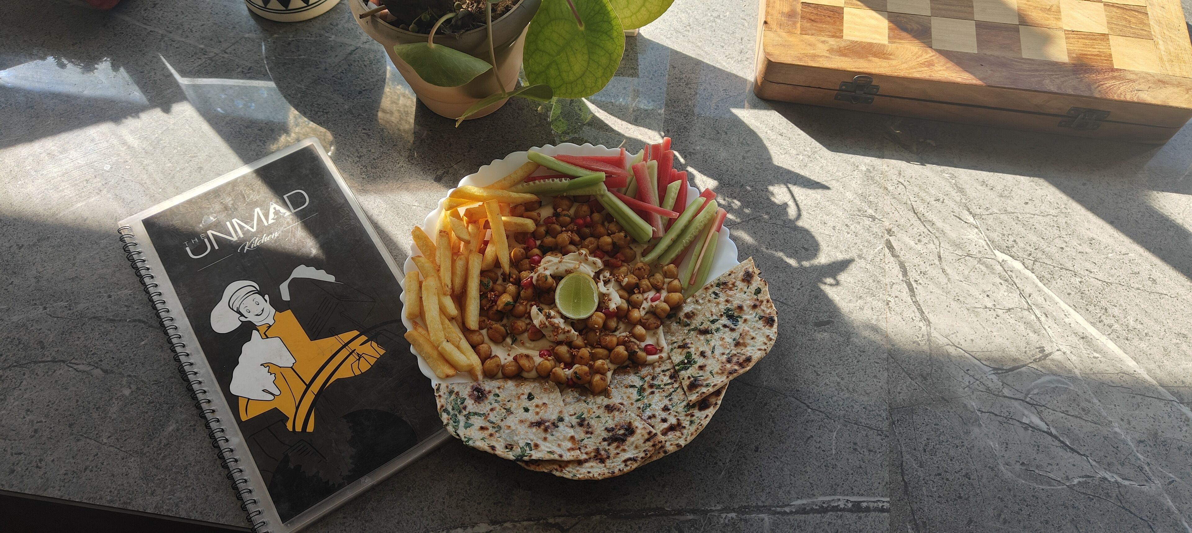 A table with a plate of food, a notebook, and a potted plant.