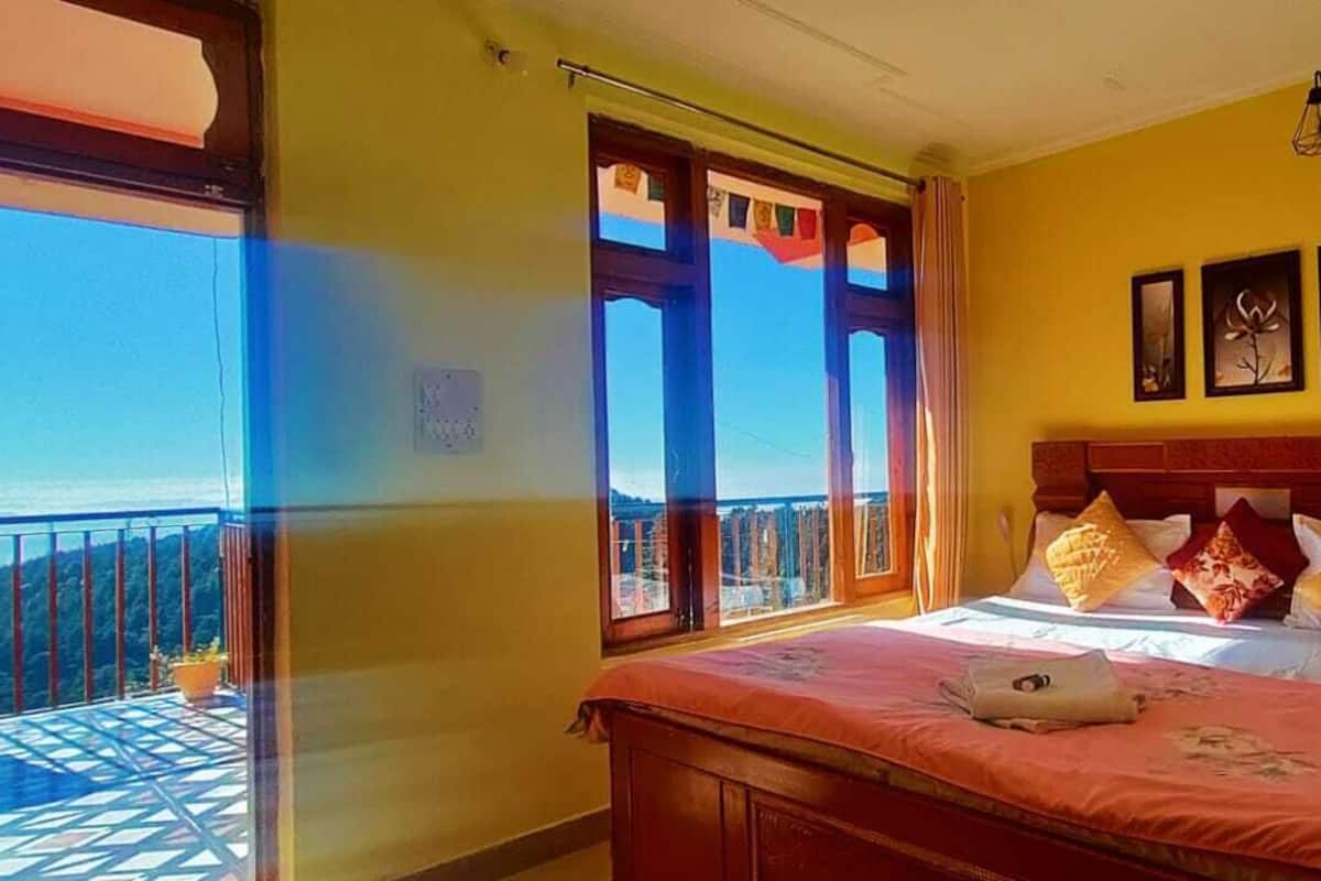 Una habitación con una cama, un ventanal con vistas y una pared decorada con tres cuadros enmarcados.