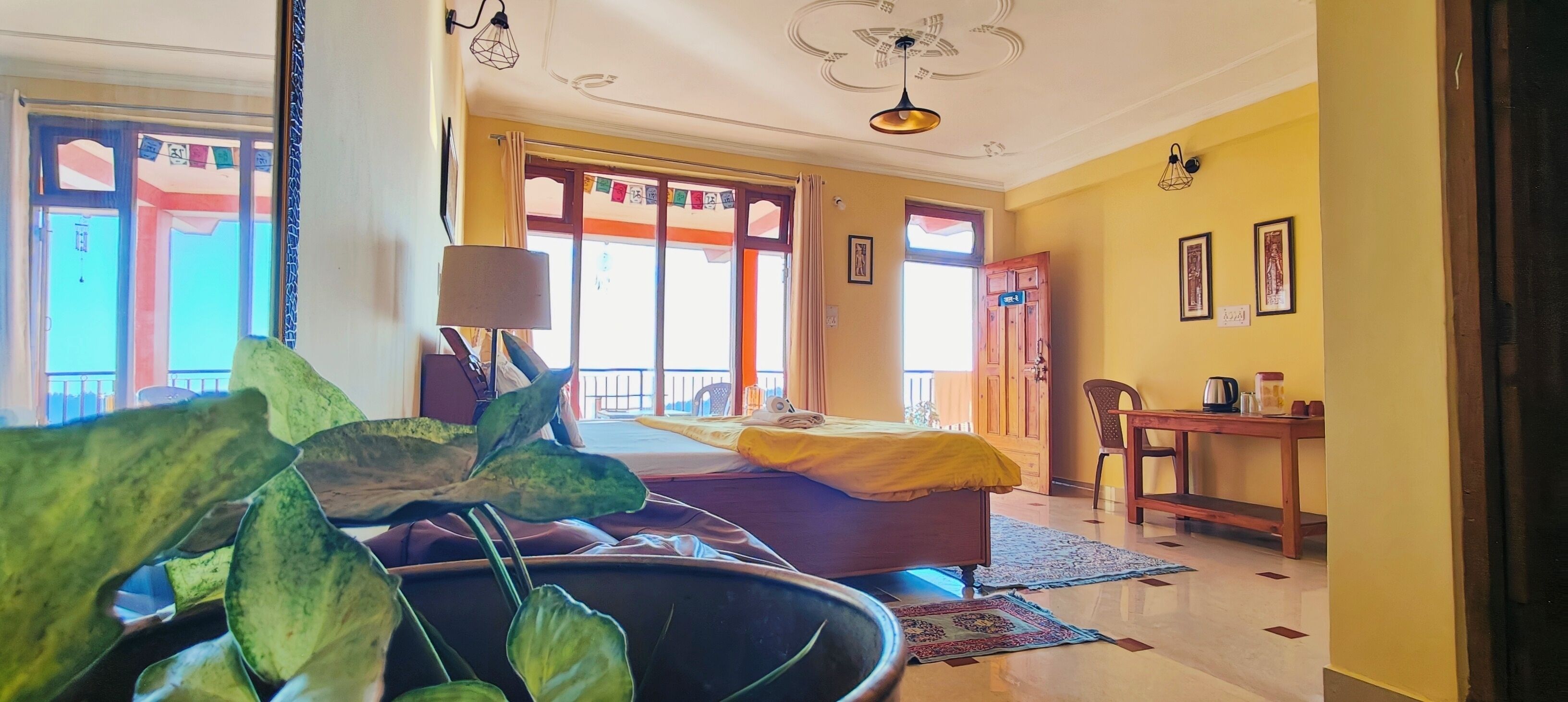 Una habitación con una cama, un escritorio, una silla y una planta grande en maceta.