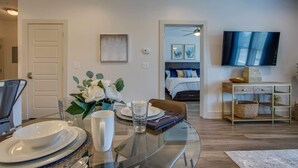 Un salon moderne avec une table à manger en verre, un canapé, un téléviseur et un lit donnant sur une vue agréable.