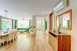 A modern living room with a dining area, a large mirror, and a wooden cabinet.