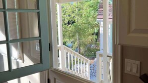 Habitación con una puerta blanca y una ventana con barandilla blanca.