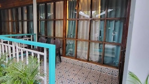 Un plafond en bois, une fenêtre avec des rideaux, un sol à motifs et une rambarde bleue.
