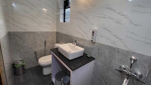 Une salle de bain moderne avec un mur en marbre, un lavabo blanc, des toilettes et un espace douche.