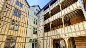 A traditional European building with multiple floors, exposed wooden beams, and a series of windows.