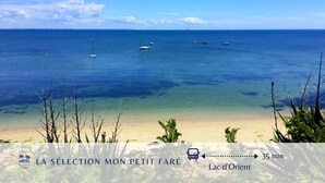 A beach with clear blue water, boats, and a sandy shore.