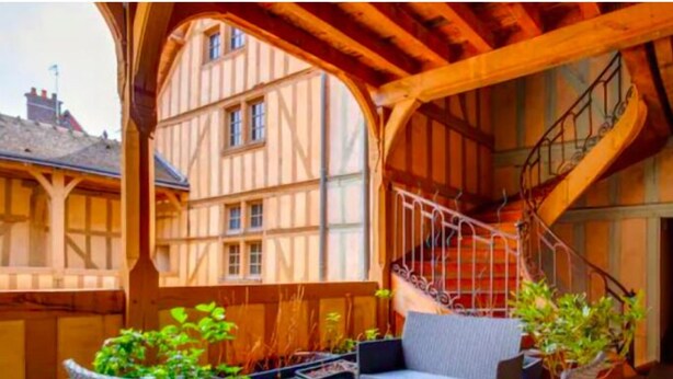 A covered outdoor area with a wooden staircase leading to a building entrance.