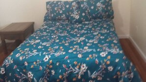 A single bed with a floral bedspread in a room with wooden flooring and a small wooden nightstand. - a nice one bedroom free parking (Schenectady)