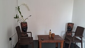 Une pièce avec deux fauteuils en osier marron, une table en bois et une plante en pot ornée de fleurs blanches.