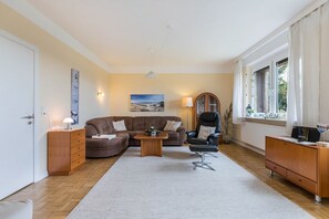 A living room with a sofa, armchair, coffee table, and a lamp. - Apartment 'Alte Schule Pahlkrug' with Private Terrace, Private Garden and Wi-Fi (Linden)