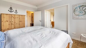 Un dormitorio con cama, armario de madera y puerta que da a otra habitación.