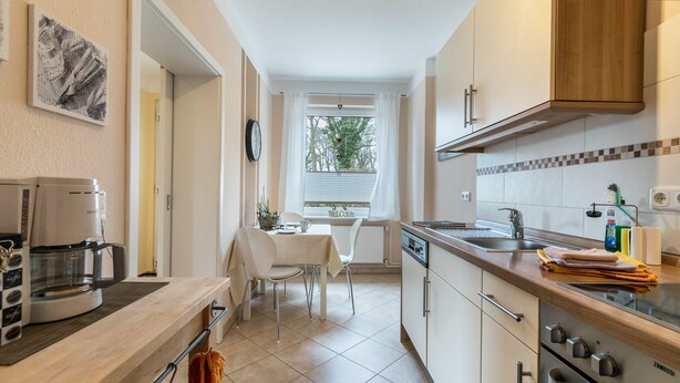 Una cocina moderna con comedor, cafetera y vistas al exterior.