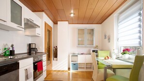 A modern kitchen with a built-in oven, a coffee maker, and a dining area with a table and chairs.
