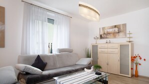 A modern living room with a sofa, a glass coffee table, a cabinet, and a painting on the wall.