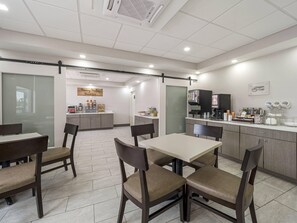 A modern breakfast area with a coffee machine, seating, and a sign reading 'Morning Melee Breakfast.' - MainStay Suites Chambersburg (Chambersburg)