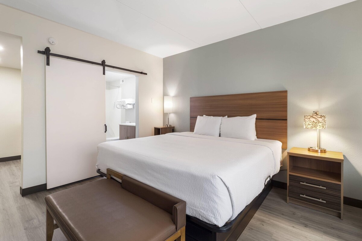 A hotel room with a bed, bedside tables, a bench, and a walk-in closet.