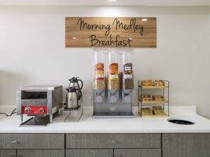 A breakfast station with a coffee maker, a sign reading 'Morning Medley Breakfast,' and various food dispensers. - MainStay Suites Chambersburg (Chambersburg)