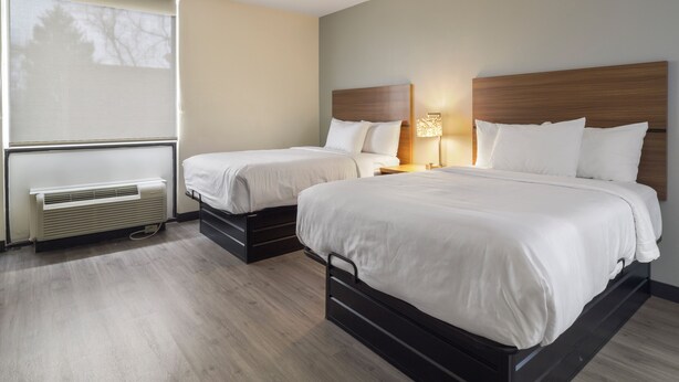 A hotel room with two beds, a heater, a lamp, and a window with a view. - MainStay Suites Chambersburg (Chambersburg)