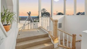 A staircase with a telescope on the landing, leading to a balcony with a view of the sunset. - Opal Cliff Overlook (Santa Cruz)