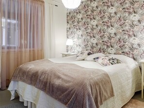 A bedroom with a bed, a nightstand, a lamp, and a floral wallpaper. - Saajola by Interhome (Enontekiö)