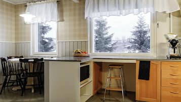 A kitchen with a central island, wooden cabinets, a built-in oven, and a window with a view of trees.