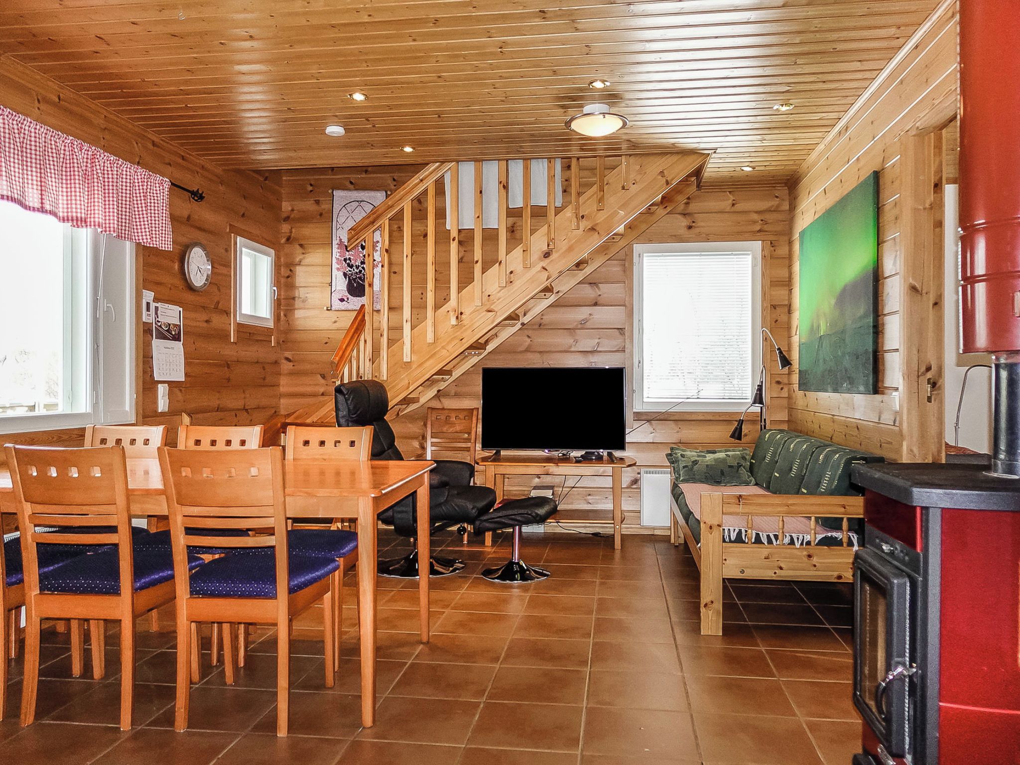 A wooden interior with a dining area, a sofa, a television, and a fireplace.
