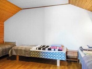A small, cozy room with two beds, a wooden ceiling, and a plain white wall.