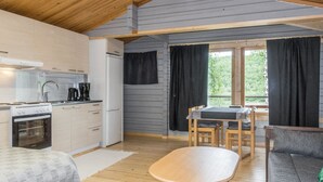 A compact kitchen with modern appliances, a dining area with a table and chairs, and a cozy seating area with a sofa. - Nilla 3 by Interhome (Utsjoki)