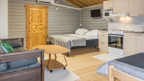 A compact room with a bed, a small table, a sofa, a kitchenette, and a wooden ceiling. - Nilla 3 by Interhome (Utsjoki)