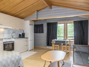 A compact kitchen with modern appliances, a dining area with a table and chairs, and a view through large windows.