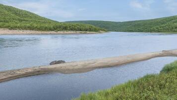 A river with a sandy bank and a log in the water.