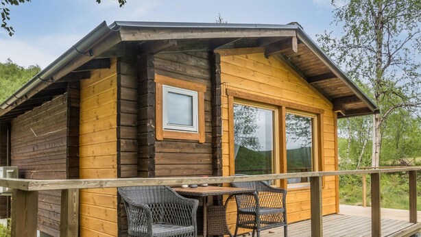 A wooden cabin with a deck, two wicker chairs, and a table. - Nilla 3 by Interhome (Utsjoki)