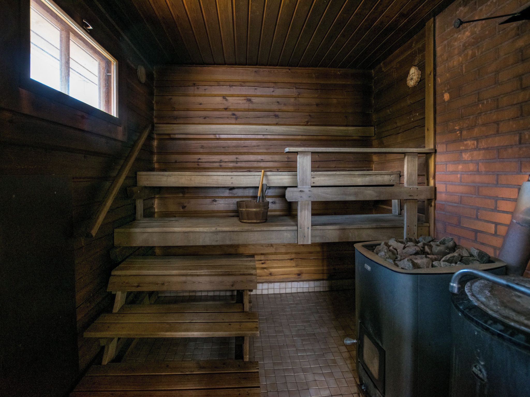 A wooden interior with a fireplace, a metal bucket, and a brick wall.