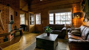 Een gezellig chalet interieur met houten details, een open haard, een bank en een eettafel.