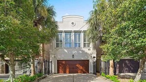 A two-story house with a garage, surrounded by trees and a well-maintained lawn. - Luxurious 3BR 2.5BA Home with Hot Tub in Top Area (Houston)