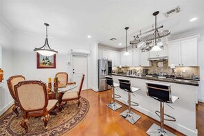A modern kitchen with white cabinets, stainless steel appliances, and a bar area with stools.
