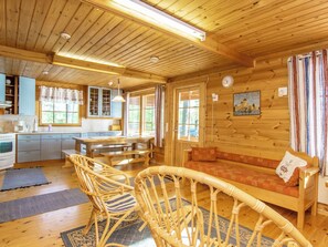 Interior de una cabaña de madera con cocina, comedor y sofá.