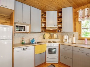 Une cuisine de taille réduite avec des meubles blancs, un four à micro-ondes, une cuisinière et un lave-vaisselle.