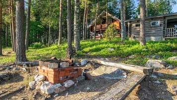 Eine Hütte, umgeben von Wald, mit einem Stapel Ziegelsteinen und Baumaterialien.