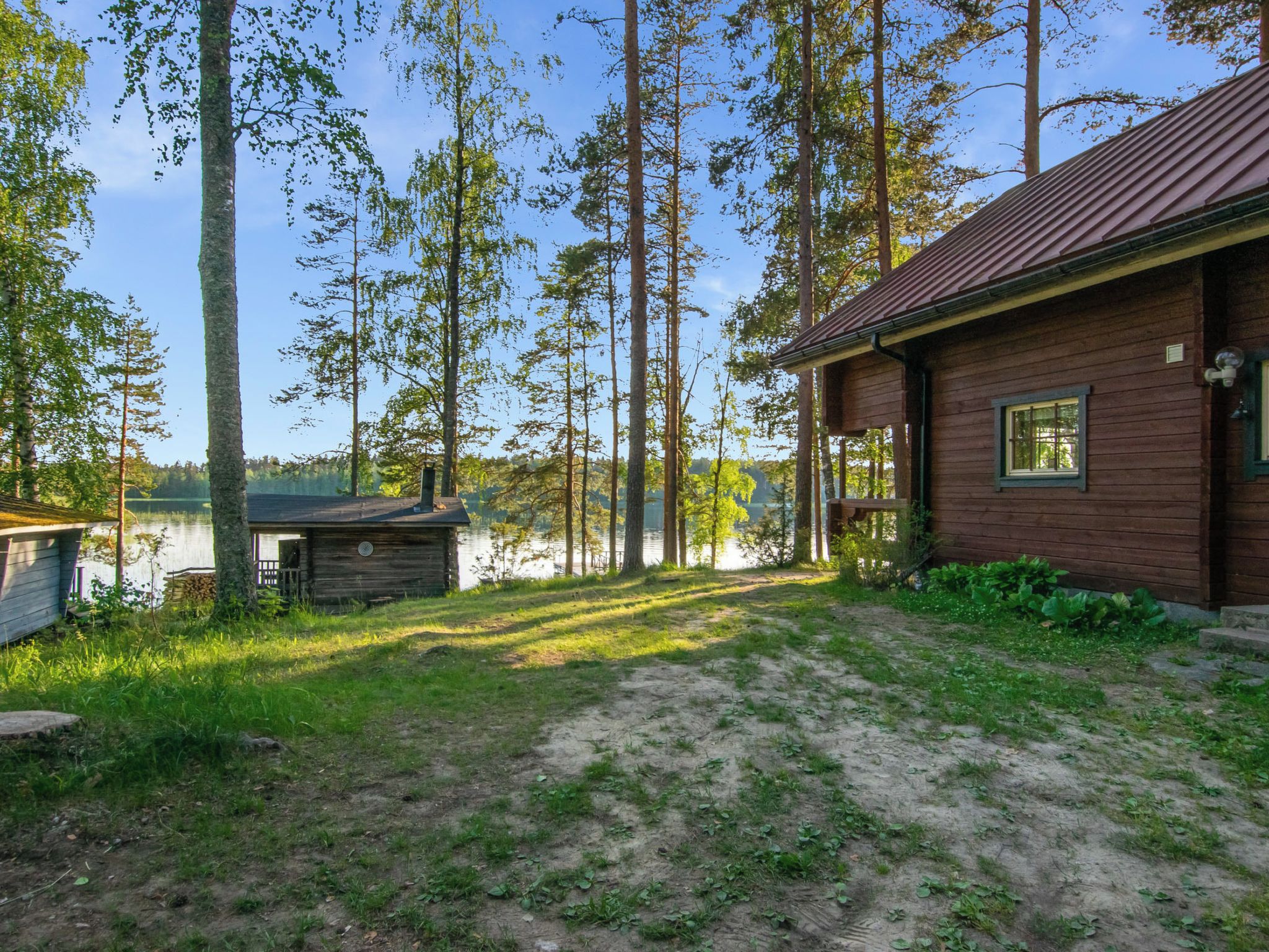 Eine Holzhütte mit Veranda und Blick auf einen von Bäumen umgebenen See.