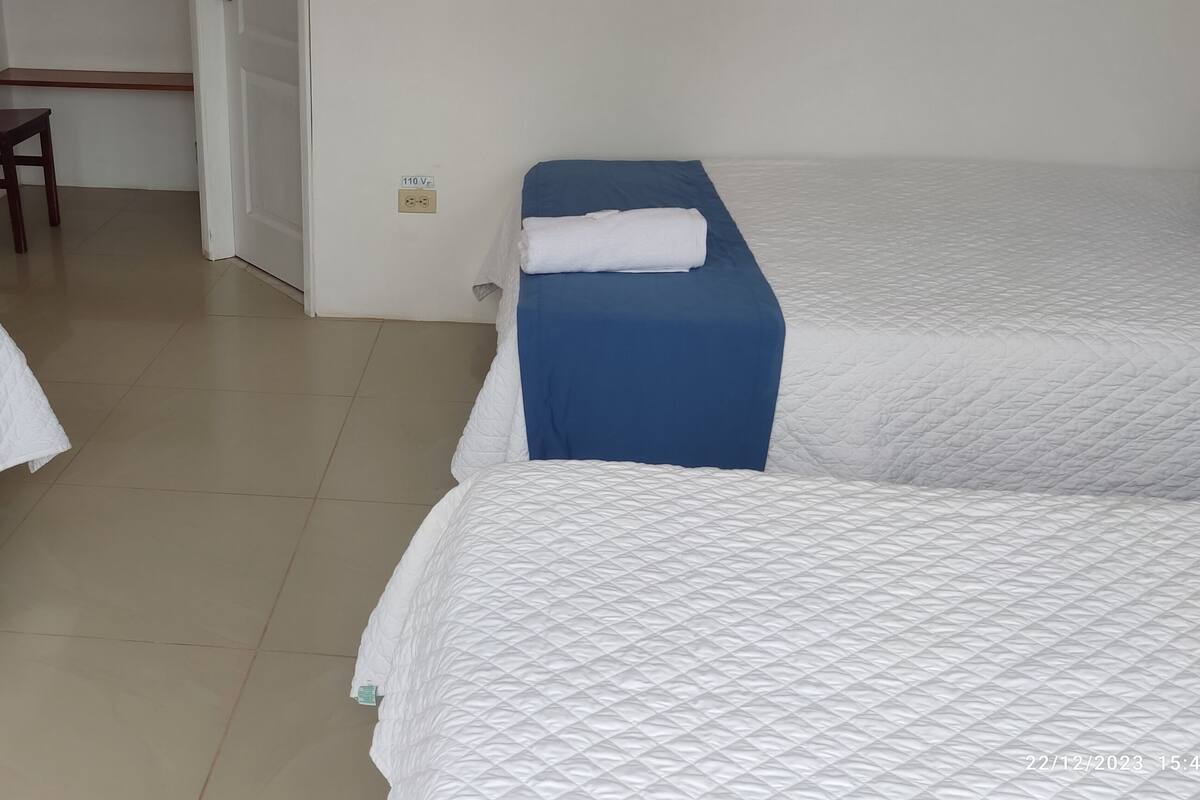 Une chambre d’hôtel avec deux lits, une petite table et une chaise, et une porte.