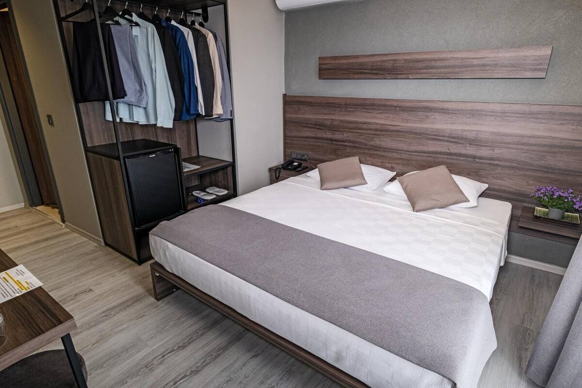 A hotel room with a bed, a wardrobe, a nightstand, and a small table.