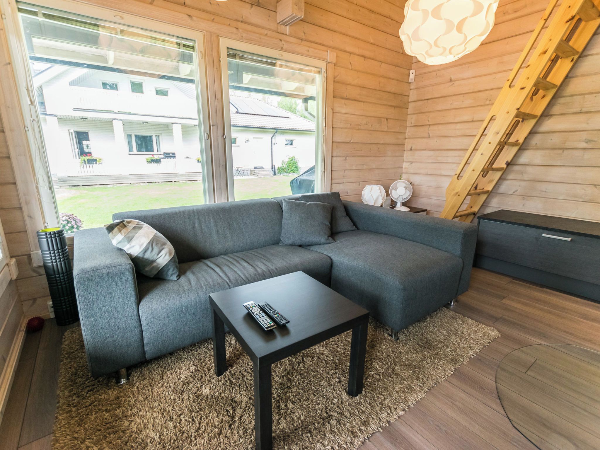 A modern living room with a grey sectional sofa, a small black coffee table, and a large window providing a view of the outside.