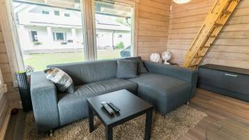 A modern living room with a grey sectional sofa, a small black coffee table, and a large window providing a view of the outside.