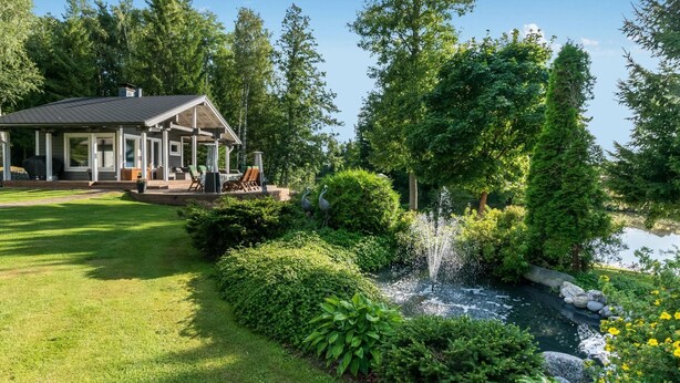 A house with a covered patio and a pond with a fountain.