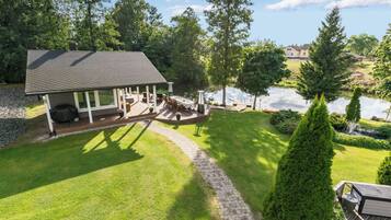 A house with a deck, a pond, and a well-maintained lawn.