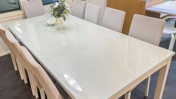 A modern dining table with a glass top and six chairs.