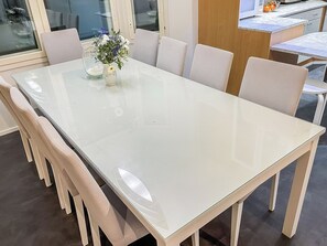 Een moderne eettafel met een glazen blad en zes stoelen.