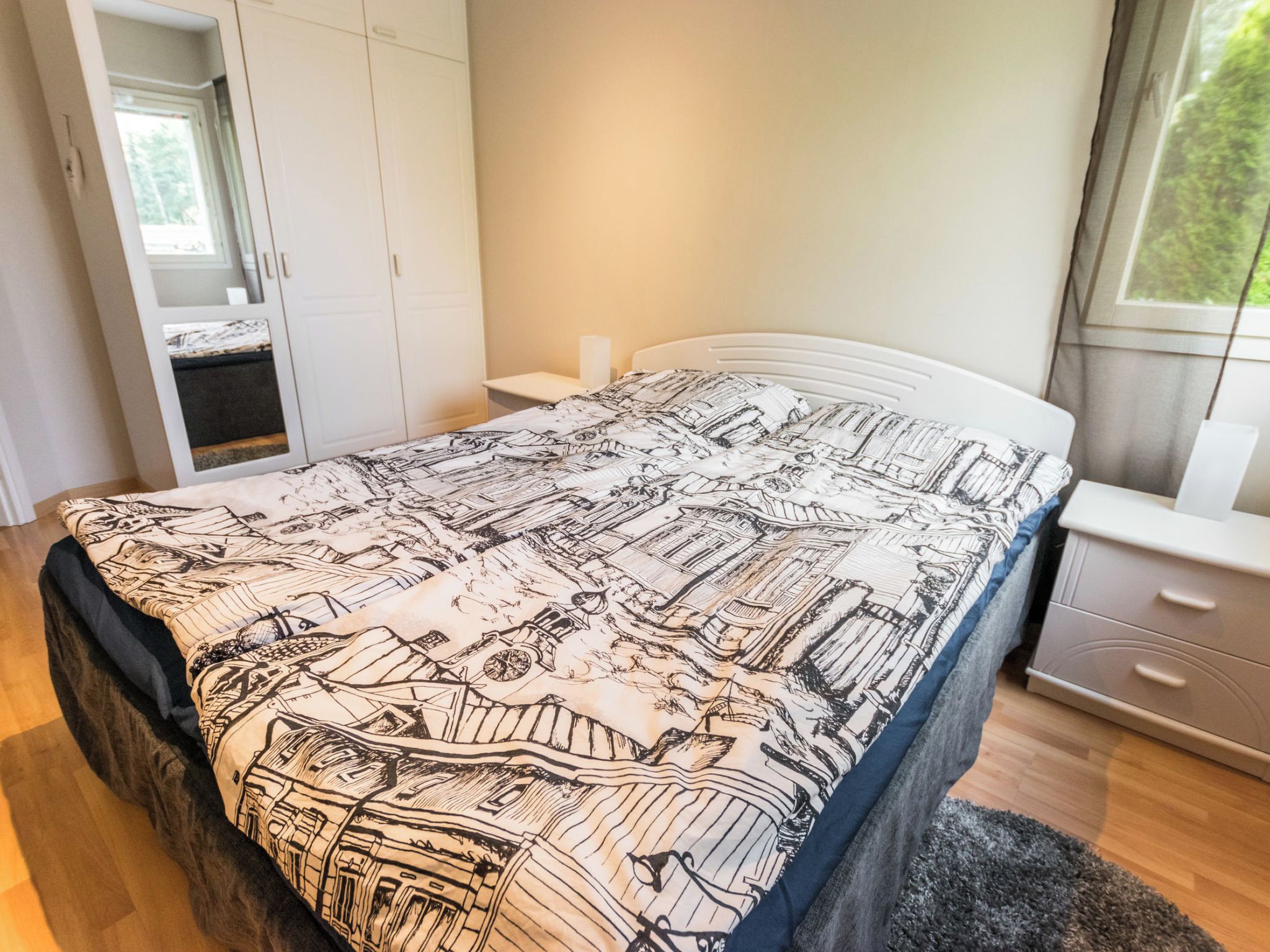 A bedroom with a bed, a nightstand, a dresser, and a window.